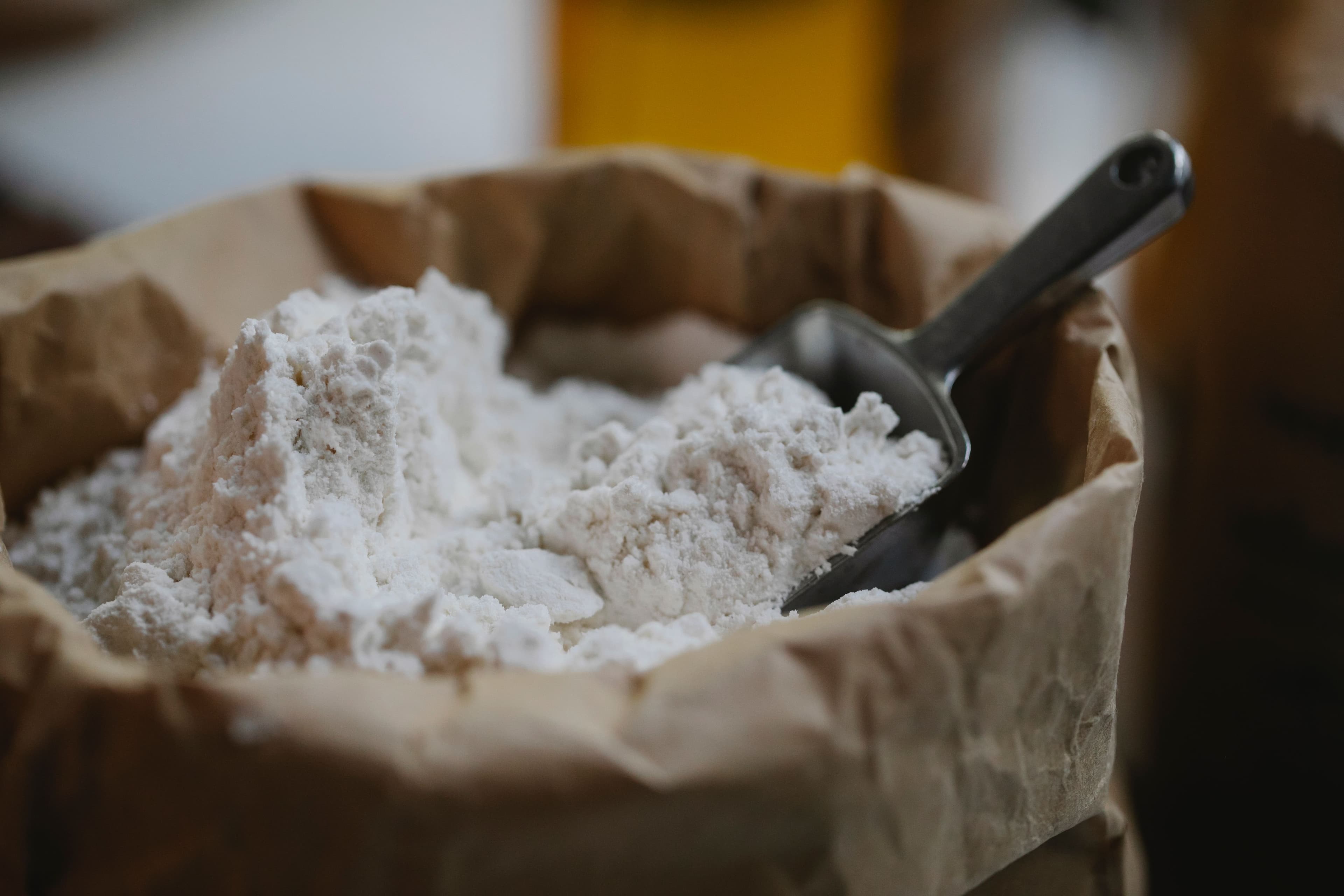 Flour in an unbranded paper bag with a metal scoop